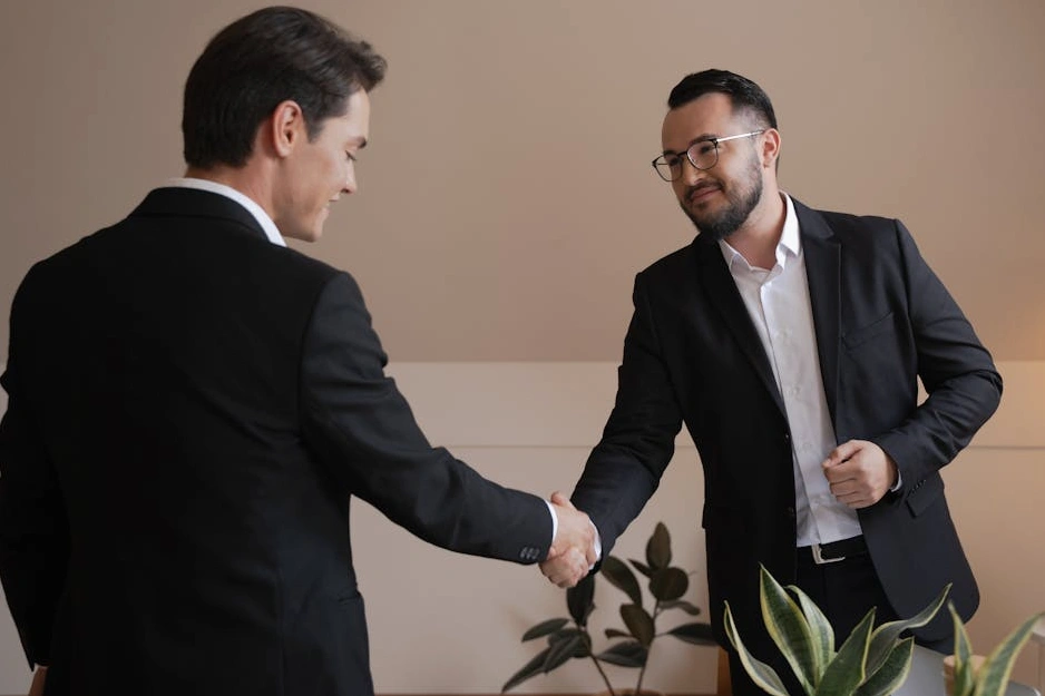 A senior business consultant shaking hands with a client in an office.